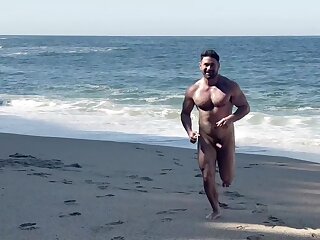 Nude hunk shows off his cock on a beach