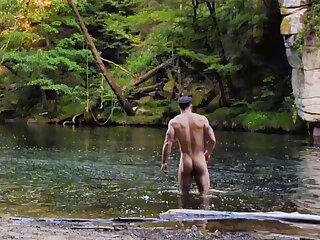 Muscular guy strips down to cool off in the river. Exposing his nude body in nature makes his cock hard, so he shamelessly jerks off and cums right there in the open (exhibitionism)