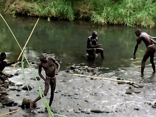Young Surma boys painting body at the river before de ceremony of stick fighting